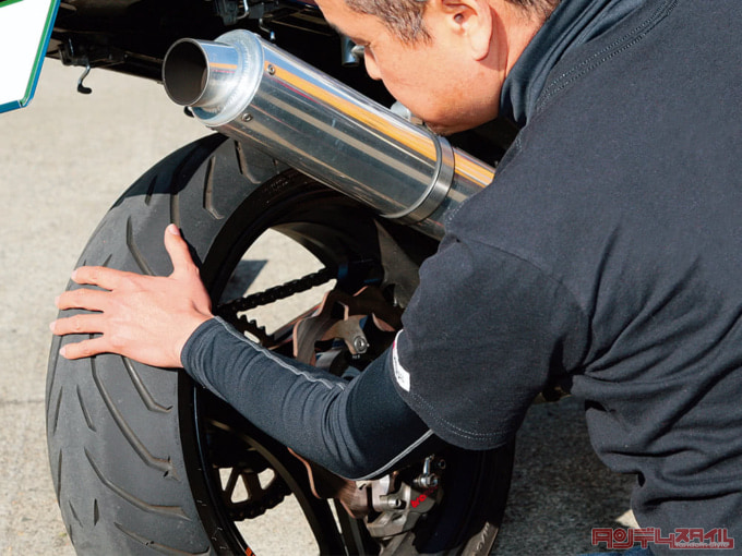 バイクのタイヤ表面を触って温度を確かめている様子