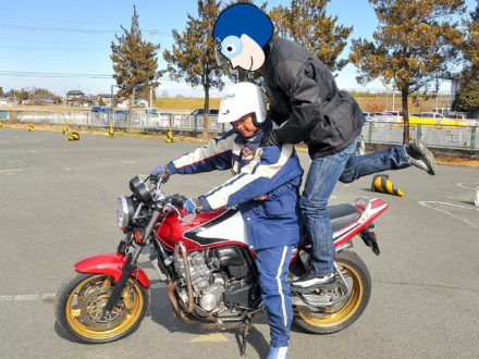 バイクの二人乗り タンデマーがステップに足をかけて跨っている様子