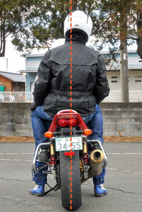 サイドスタンドをかけたバイクに乗っているタンデマーが地面に対し垂直に座っている状態