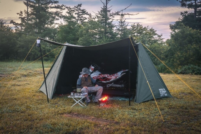 バイクも収納できるNEUN PUP TENT の中でくつろぐライダー