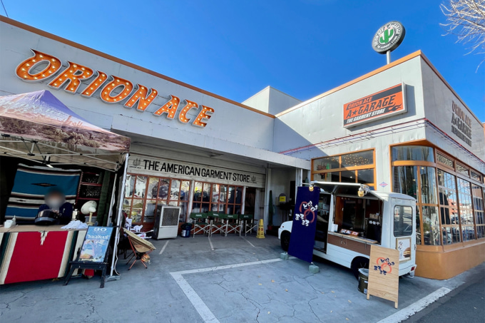 調布にあるオリオンエース直営店『ORIONACE A★GARAGE』の外観。店舗前にはフードトラックやテントブースが並び、アメカジの雰囲気が漂う。